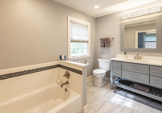 bathroom with toilet, a garden tub, vanity, baseboards, and recessed lighting