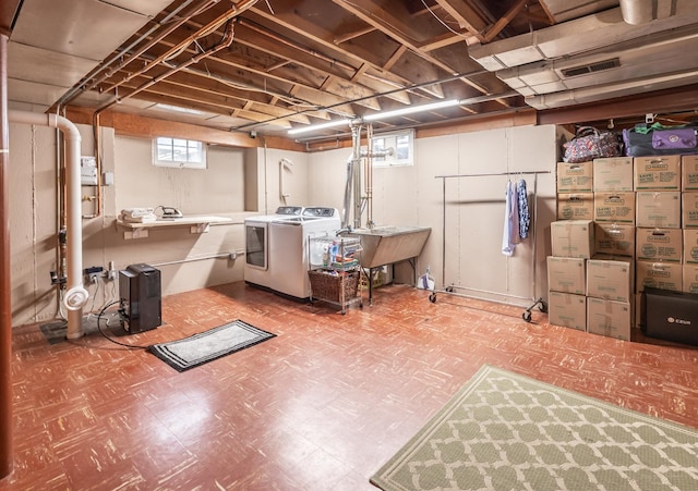 below grade area featuring tile patterned floors, washer and dryer, and a sink