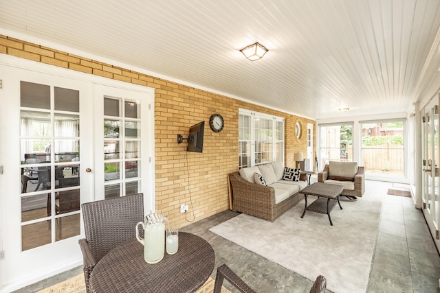 sunroom / solarium with brick wall, outdoor lounge area, wood ceiling, and french doors