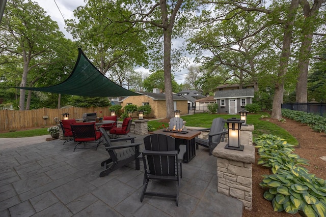 view of patio / terrace featuring an outdoor fire pit, a fenced backyard, an outdoor structure, outdoor dining area, and a shed