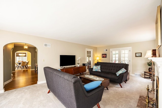 living room with arched walkways, light colored carpet, and baseboards