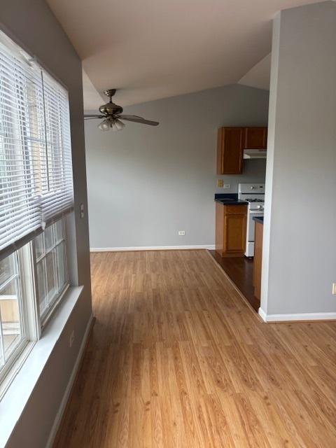 1286 N Red Oak Cir Unit 4, Round Lake Beach, IL 60073 - unfurnished living room with ceiling fan, light wood-style flooring, baseboards, and vaulted ceiling
