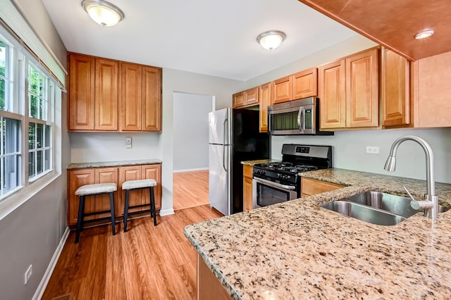 1400 Carleton Ave, Naperville, IL 60565 - kitchen with appliances with stainless steel finishes, a sink, light stone countertops, light wood finished floors, and baseboards