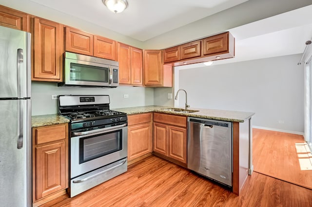 1400 Carleton Ave, Naperville, IL 60565 - kitchen featuring appliances with stainless steel finishes, a sink, light wood-type flooring, a peninsula, and light stone counters