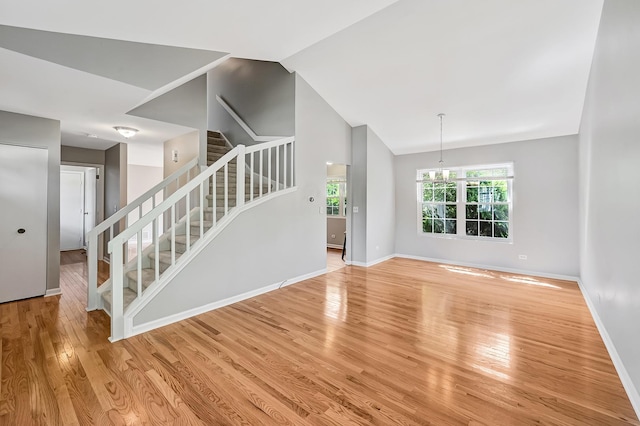 1400 Carleton Ave, Naperville, IL 60565 - unfurnished living room with stairway, light wood finished floors, baseboards, a chandelier, and vaulted ceiling