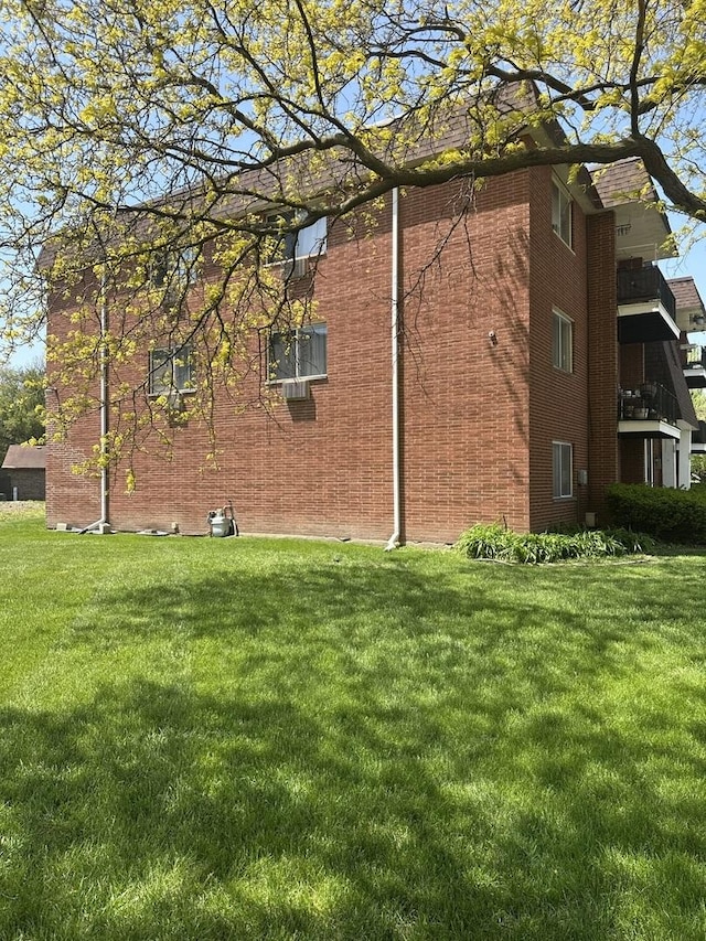 view of side of property with brick siding and a yard