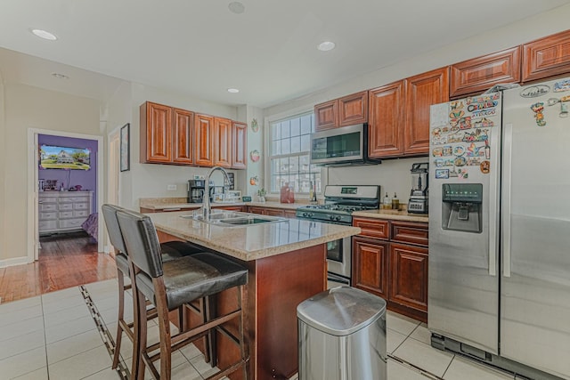kitchen featuring stainless steel appliances, a sink, light tile patterned floors, a breakfast bar area, and recessed lighting