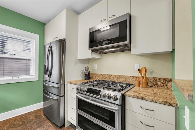 606 S Cedar St, Urbana, IL 61801 - kitchen featuring appliances with stainless steel finishes, baseboards, white cabinetry, and light stone counters