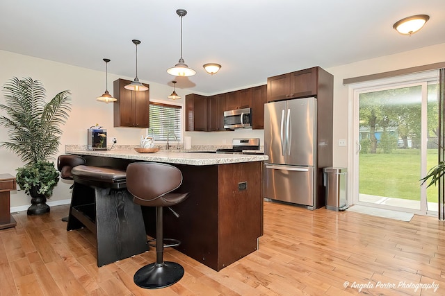 2505 S Harriet Ln, Holiday Hills, IL 60051 - kitchen with stainless steel appliances, light wood-type flooring, a peninsula, light countertops, and dark brown cabinetry