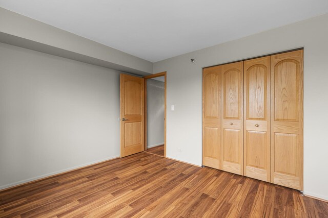 unfurnished bedroom with wood finished floors, a closet, and baseboards