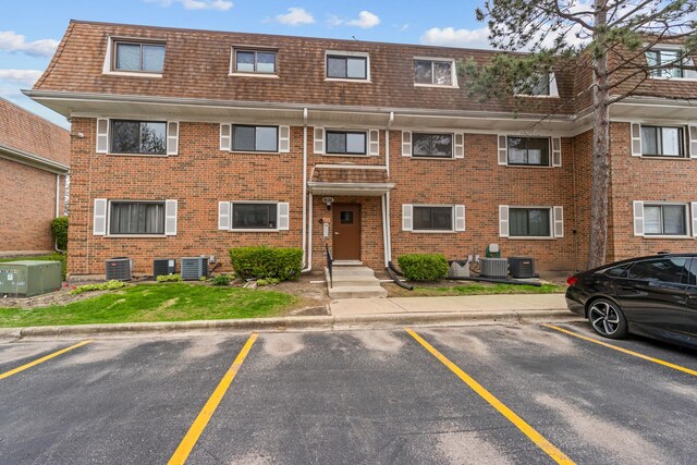 view of apartment building / complex featuring cooling unit and uncovered parking