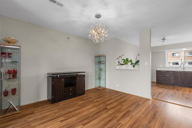 unfurnished living room featuring wood finished floors, a chandelier, and a sink