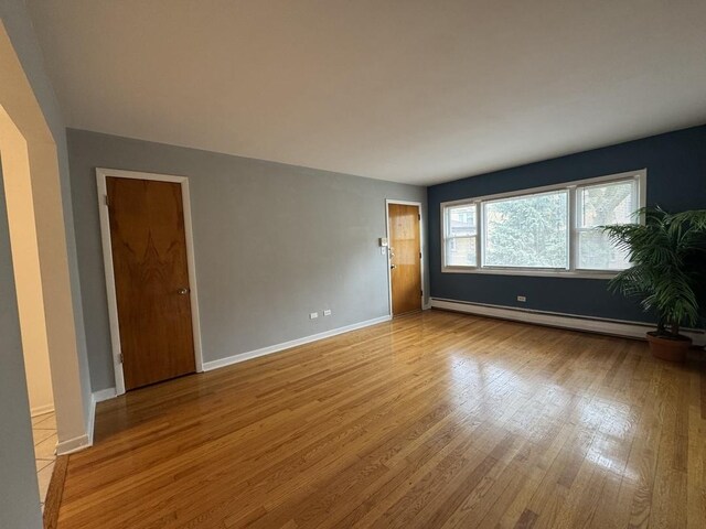 4456 W Gunnison St Unit 2A, Chicago, IL 60630 - empty room featuring a baseboard heating unit, wood finished floors, and baseboards