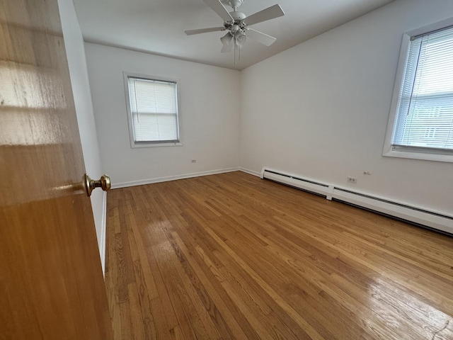 4456 W Gunnison St Unit 2A, Chicago, IL 60630 - spare room featuring wood finished floors, ceiling fan, a baseboard heating unit, and baseboards
