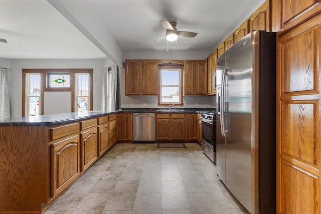 201 E Court St, Paris, IL 61944 - kitchen featuring stainless steel appliances, dark countertops, a peninsula, brown cabinets, and a ceiling fan