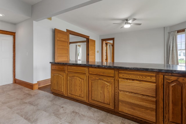 201 E Court St, Paris, IL 61944 - kitchen with baseboards, brown cabinetry, ceiling fan, and dark stone countertops