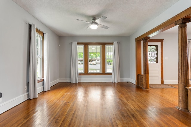 201 E Court St, Paris, IL 61944 - spare room featuring ornate columns, a ceiling fan, healthy amount of natural light, wood finished floors, and a textured ceiling