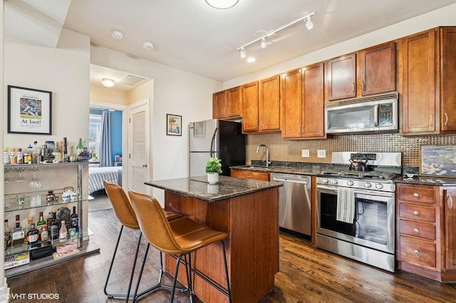 2217 W Foster Ave Unit 1, Chicago, IL 60625 - kitchen with appliances with stainless steel finishes, a sink, dark wood-style floors, a kitchen island, and a breakfast bar