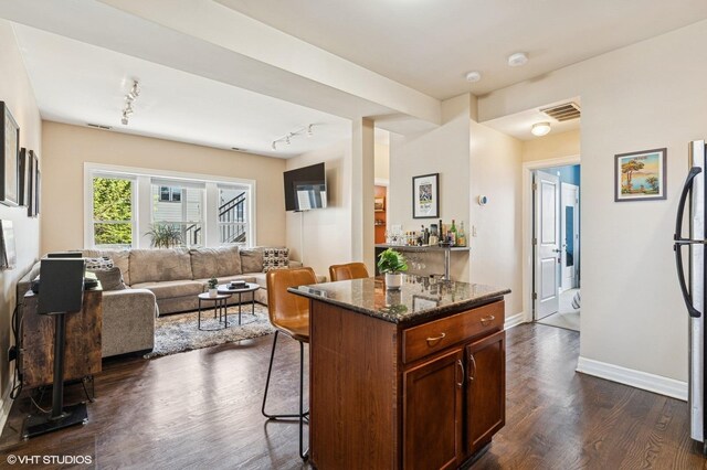 2217 W Foster Ave Unit 1, Chicago, IL 60625 - kitchen featuring a breakfast bar area, dark wood-type flooring, open floor plan, dark stone countertops, and baseboards