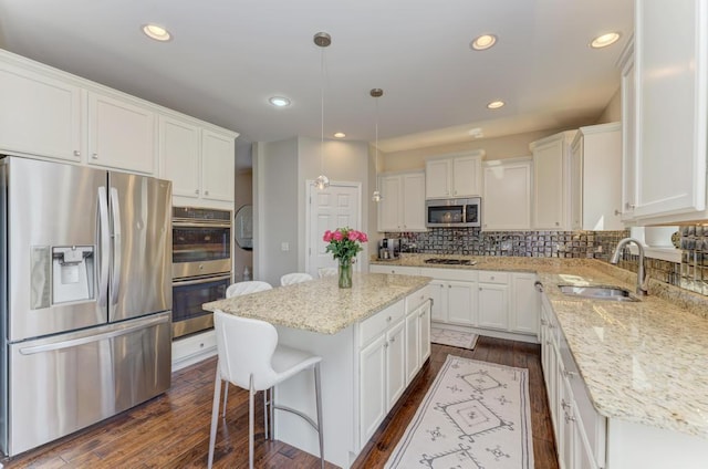 141 Bluegrass Pkwy, Oswego, IL 60543 - kitchen with stainless steel appliances, a sink, white cabinetry, dark wood-style floors, and a center island