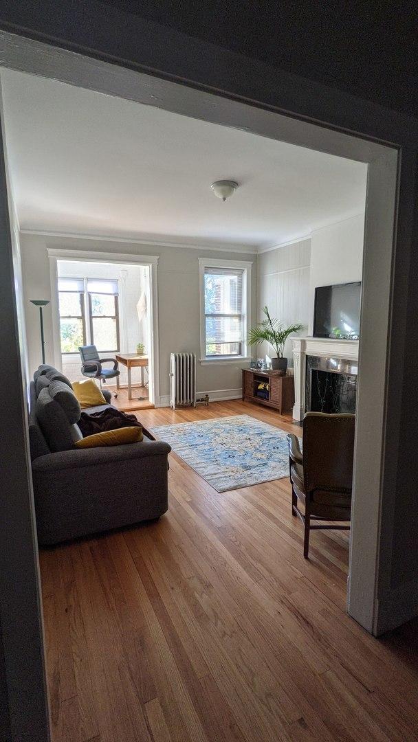 5110 S Woodlawn Ave Unit 3H, Chicago, IL 60615 - living room featuring radiator heating unit, wood finished floors, and a fireplace