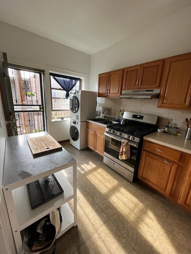 5110 S Woodlawn Ave Unit 3H, Chicago, IL 60615 - kitchen featuring stainless steel range with gas stovetop, stacked washer and clothes dryer, brown cabinets, under cabinet range hood, and backsplash
