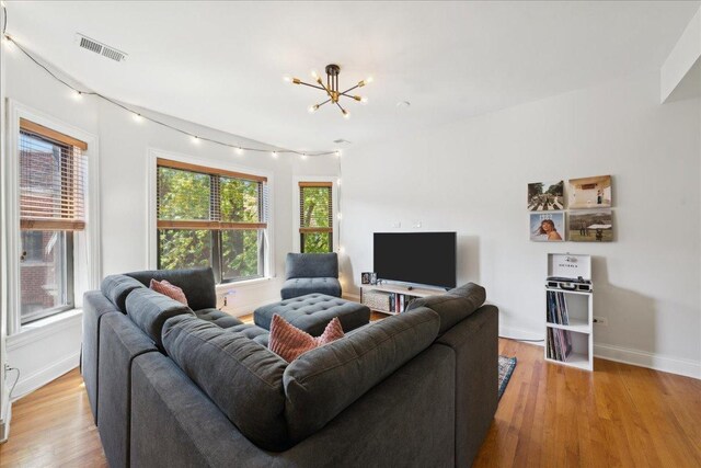living room featuring a chandelier, baseboards, and light wood-style floors