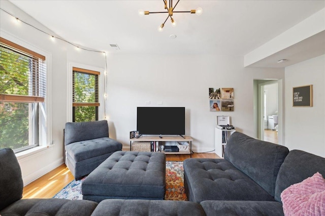 living area featuring wood finished floors, healthy amount of natural light, a chandelier, and baseboards