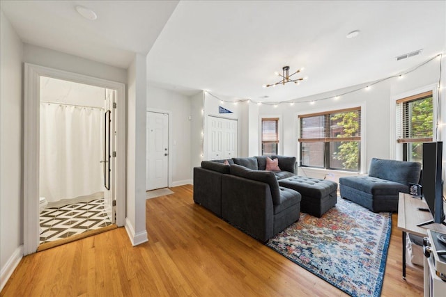 living area with light wood-style flooring, baseboards, and a chandelier
