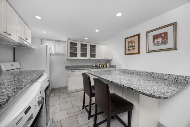 4316 N Sayre Ave, Norridge, IL 60706 - kitchen with washer / dryer, a breakfast bar, glass insert cabinets, white cabinetry, and recessed lighting