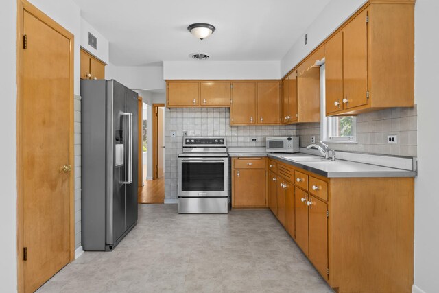 4316 N Sayre Ave, Norridge, IL 60706 - kitchen with stainless steel appliances, a sink, decorative backsplash, light countertops, and brown cabinets
