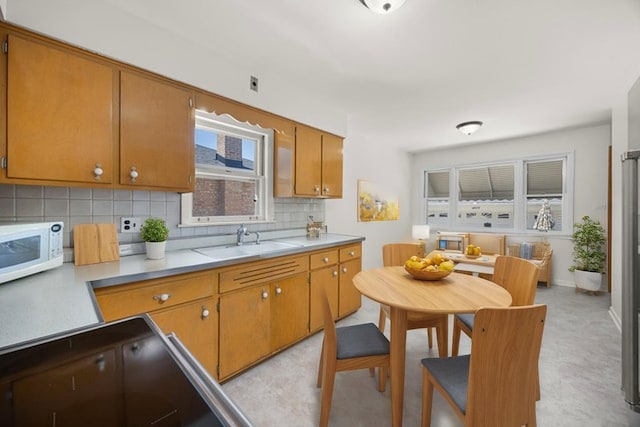 4316 N Sayre Ave, Norridge, IL 60706 - kitchen featuring a sink, white microwave, decorative backsplash, light countertops, and brown cabinets