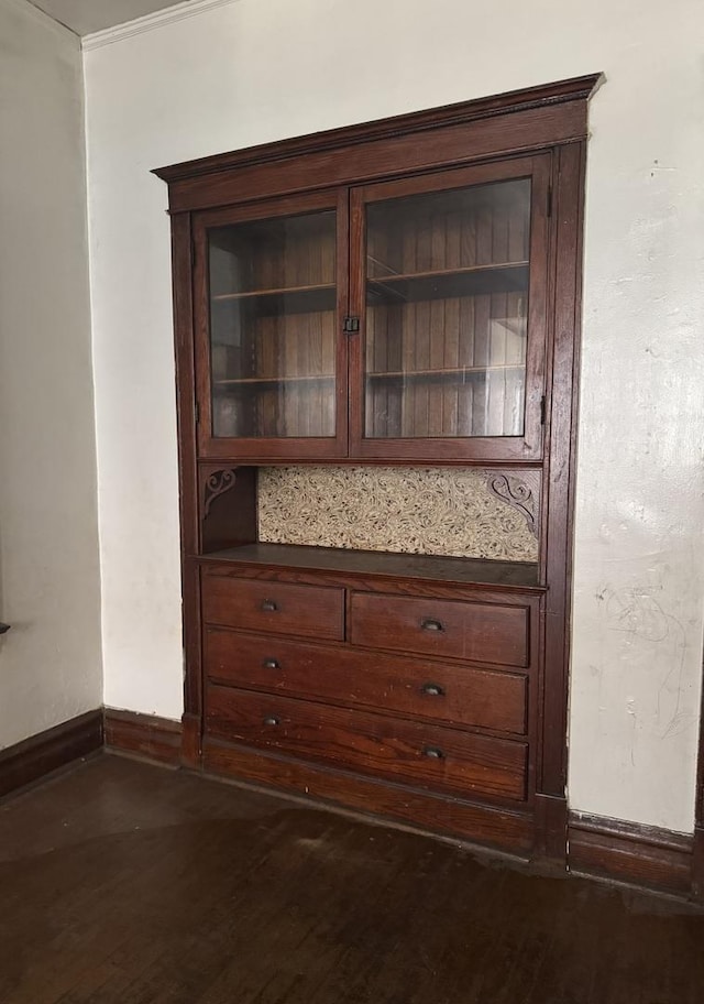 detailed view of wood finished floors, baseboards, and crown molding