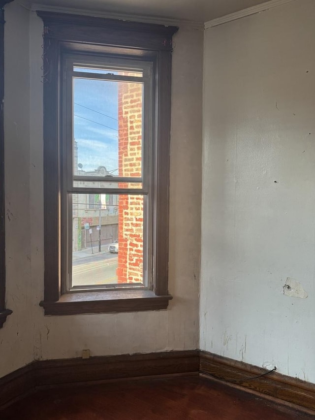 detailed view of wood finished floors, baseboards, and crown molding