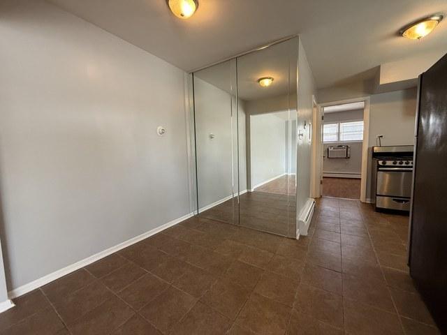 39 King Arthur Ct Unit 10, Northlake, IL 60164 - corridor with baseboards, a baseboard radiator, and dark tile patterned floors