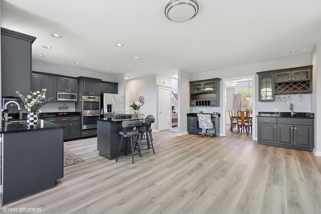 4276 Colton Cir, Naperville, IL 60564 - kitchen with stainless steel appliances, a sink, dark countertops, a breakfast bar area, and light wood-style floors