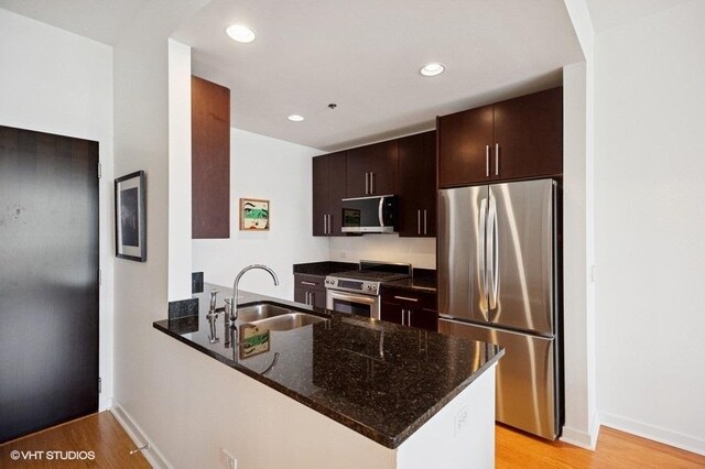 303 W Ohio St Unit 1509, Chicago, IL 60654 - kitchen featuring appliances with stainless steel finishes, a sink, a peninsula, dark stone countertops, and recessed lighting