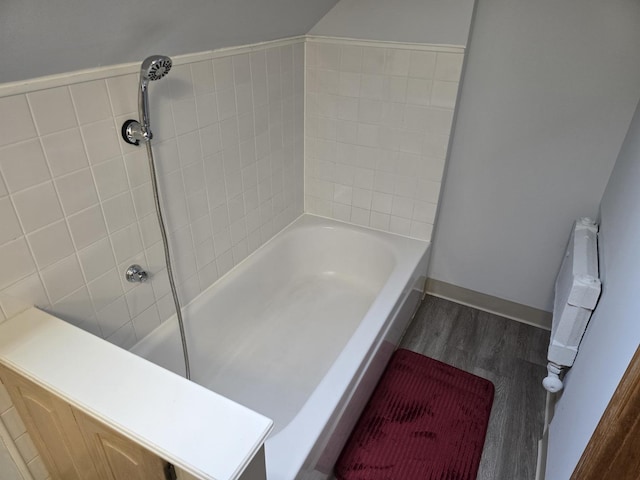 bathroom featuring wood finished floors, a shower, a tub, and baseboards