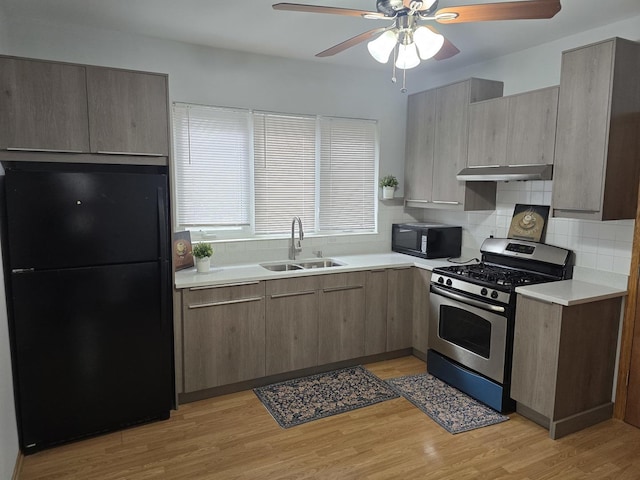 kitchen featuring black appliances, a sink, under cabinet range hood, ceiling fan, and light countertops