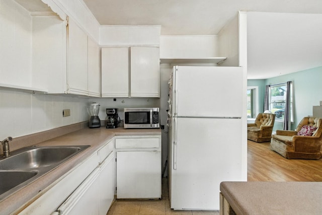 1724 Sycamore Ave, Hanover Park, IL 60133 - kitchen featuring freestanding refrigerator, stainless steel microwave, white cabinetry, and light countertops
