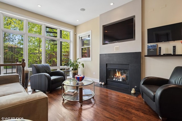 living area featuring wood finished floors, a fireplace with flush hearth, baseboards, and recessed lighting