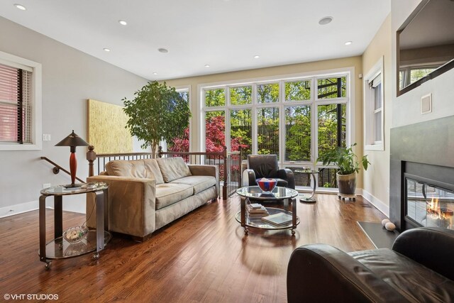 living area with wood finished floors, a fireplace with flush hearth, baseboards, and recessed lighting