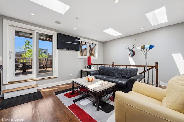 living area with a skylight, plenty of natural light, wood finished floors, and recessed lighting
