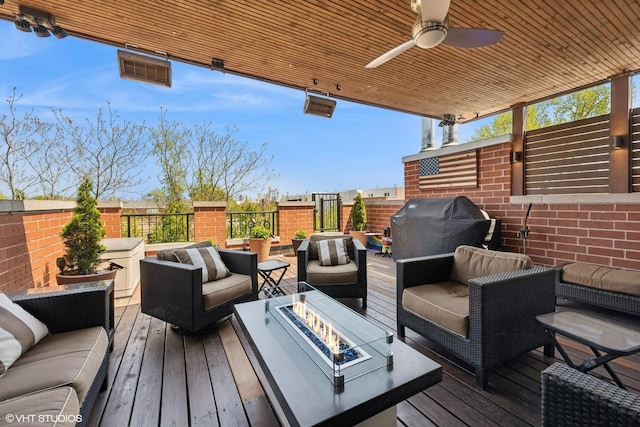 wooden deck with an outdoor living space with a fire pit and ceiling fan