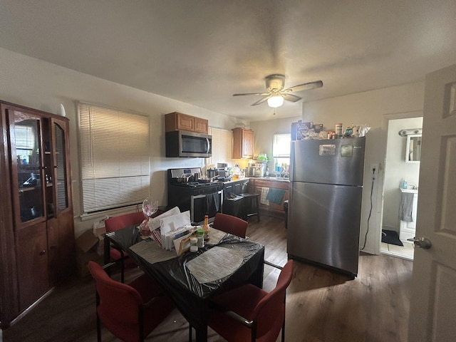 kitchen with appliances with stainless steel finishes, dark wood finished floors, a ceiling fan, and brown cabinets