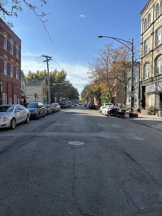 view of asphalt road featuring street lighting, sidewalks, and curbs