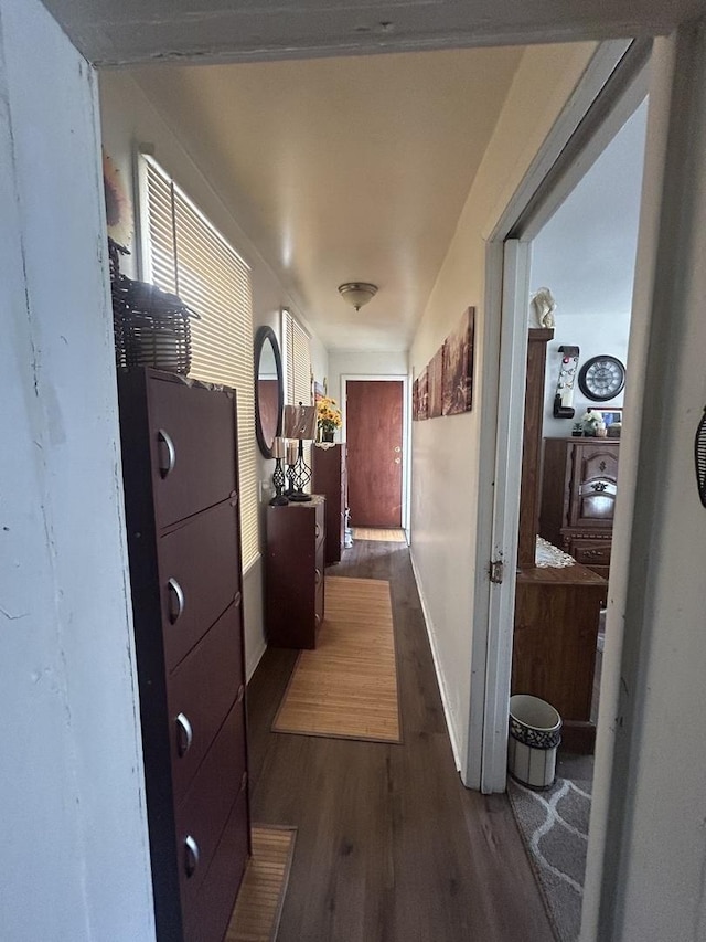 hall featuring dark wood-type flooring and baseboards
