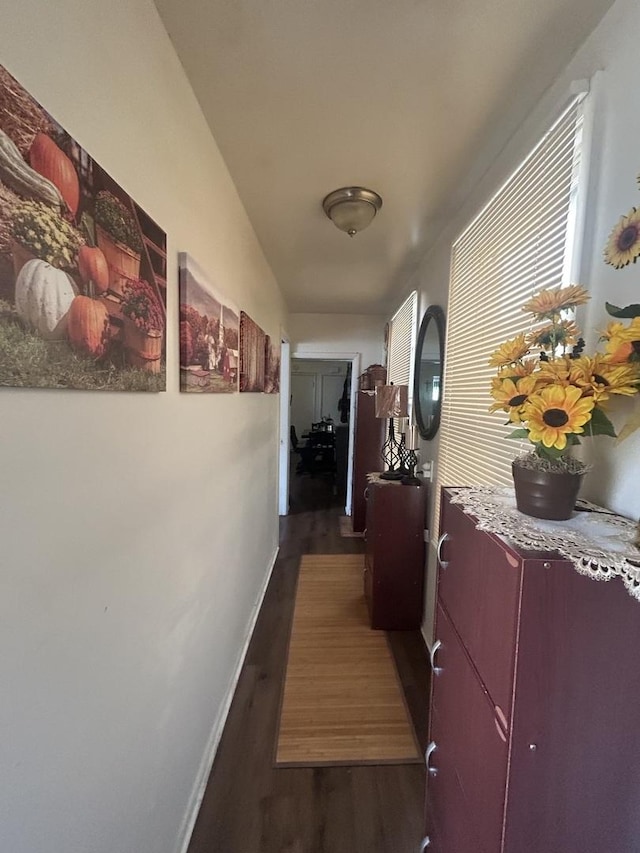 corridor featuring dark wood-style flooring and baseboards