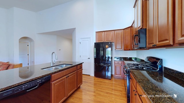 1400 Colchester Ln, Aurora, IL 60505 - kitchen with black appliances, a sink, a high ceiling, arched walkways, and light wood finished floors