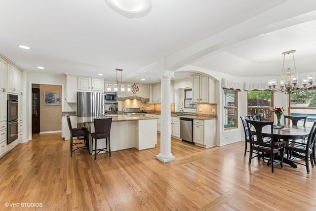 506 Rodney St, Lockport, IL 60441 - kitchen with appliances with stainless steel finishes, a center island, decorative columns, light wood-type flooring, and light stone countertops